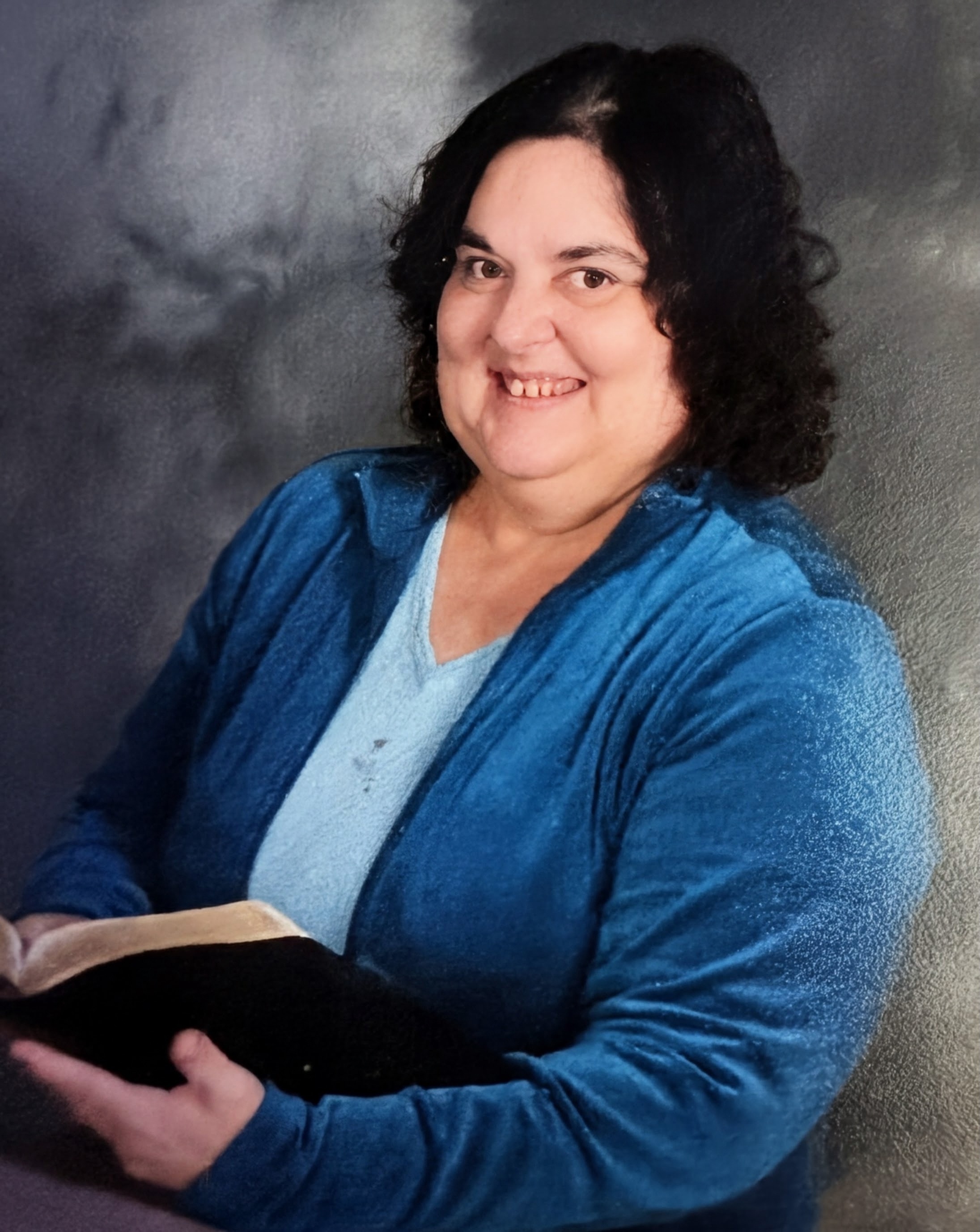 Author Judy Sain Kirkpatrick smiling warmly, holding an open Bible.